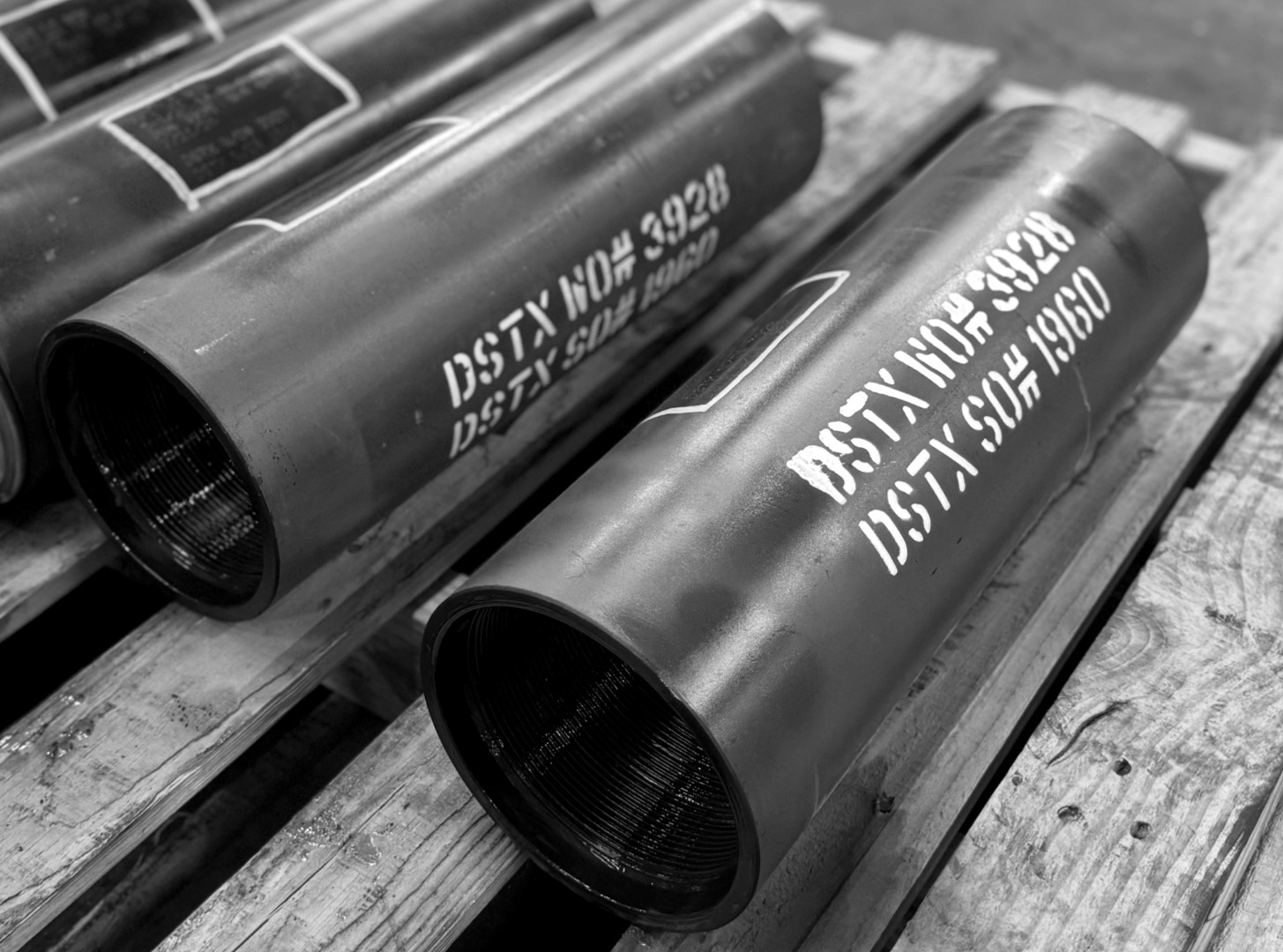 Black-and-white close-up of Delta Solutions branded casing joints with tally markings staged on wood pallets