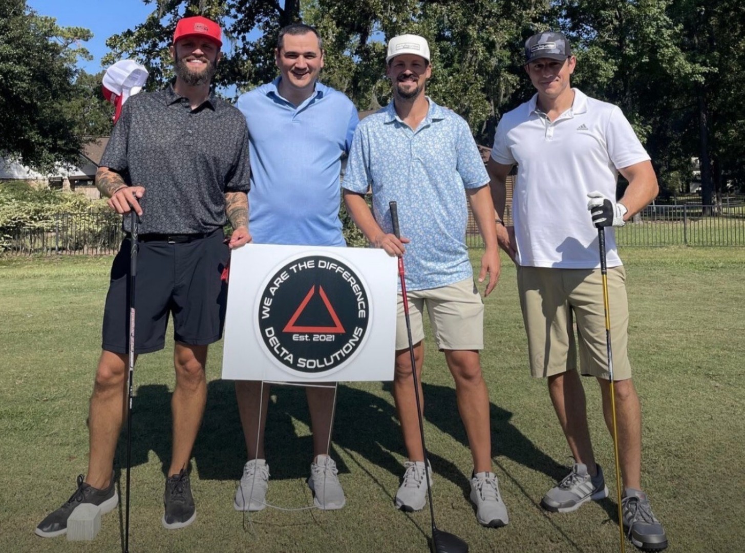 Delta Solutions team at a golf tournament with the company sign