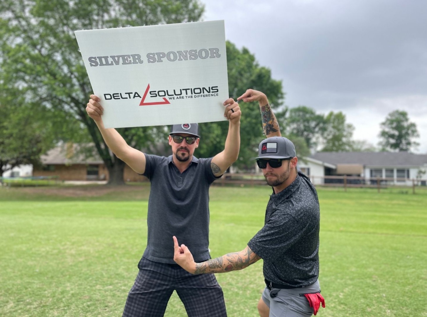 Delta Solutions team holding a Silver Sponsor sign at a golf event
