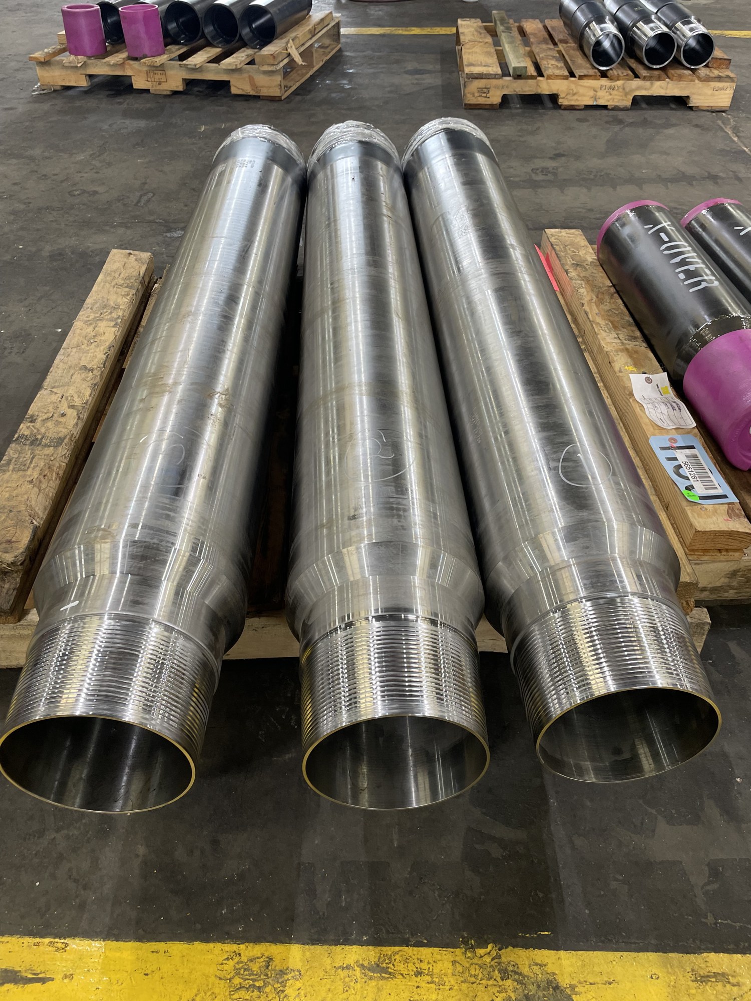 Three freshly machined casing joints with premium pin-end threads staged at Delta Solutions